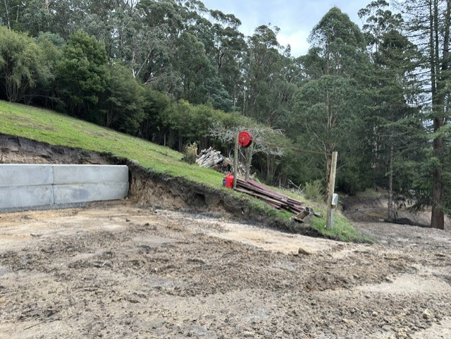 Keutmann Residence — concrete retaining wall and cut batter forming the lower driveway and building pad on the sloping site.