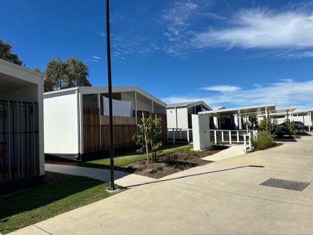 Completed community housing streetscape with planting and low-rise dwellings.